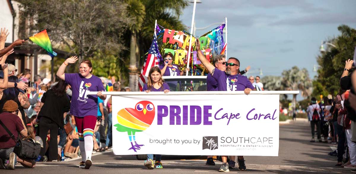 Group of PRIDE volunteers carrying a PRIDE Cape Coral banner in the PRIDE parade.